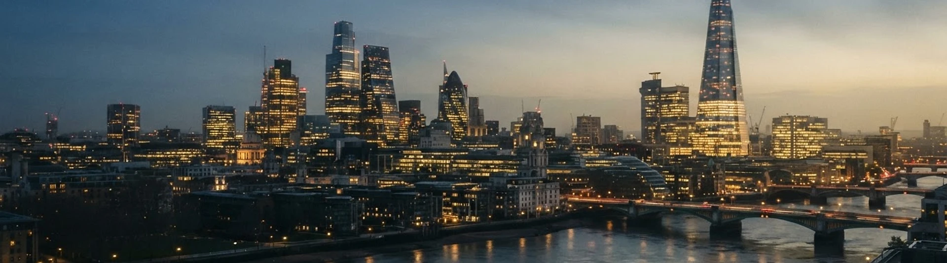 The City of London skyline at dusk, glass towers glowing against a hazy golden sky